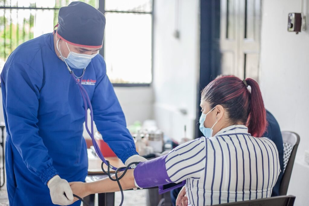 pexels-photo-12193104-12193104 A nurse performs a blood pressure check on a patient in a healthcare setting, emphasizing safety and care.